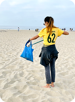 Woman cleaning up trash on Santa Monica Beach, California